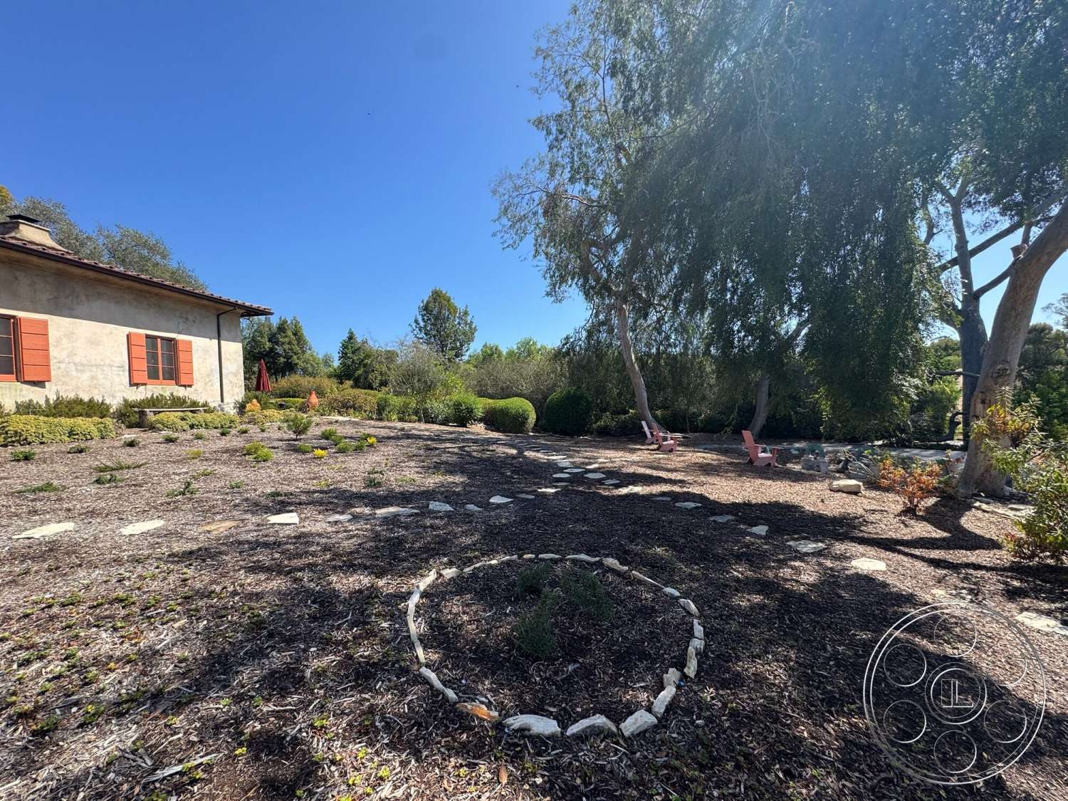 Farmstead Garden - exterior, single-story home, terraced landscaping, landscaped garden setting, stucco exterior walls, flowering shrubbery, natural stone garden path, mulched garden beds, red painted wooden shutters