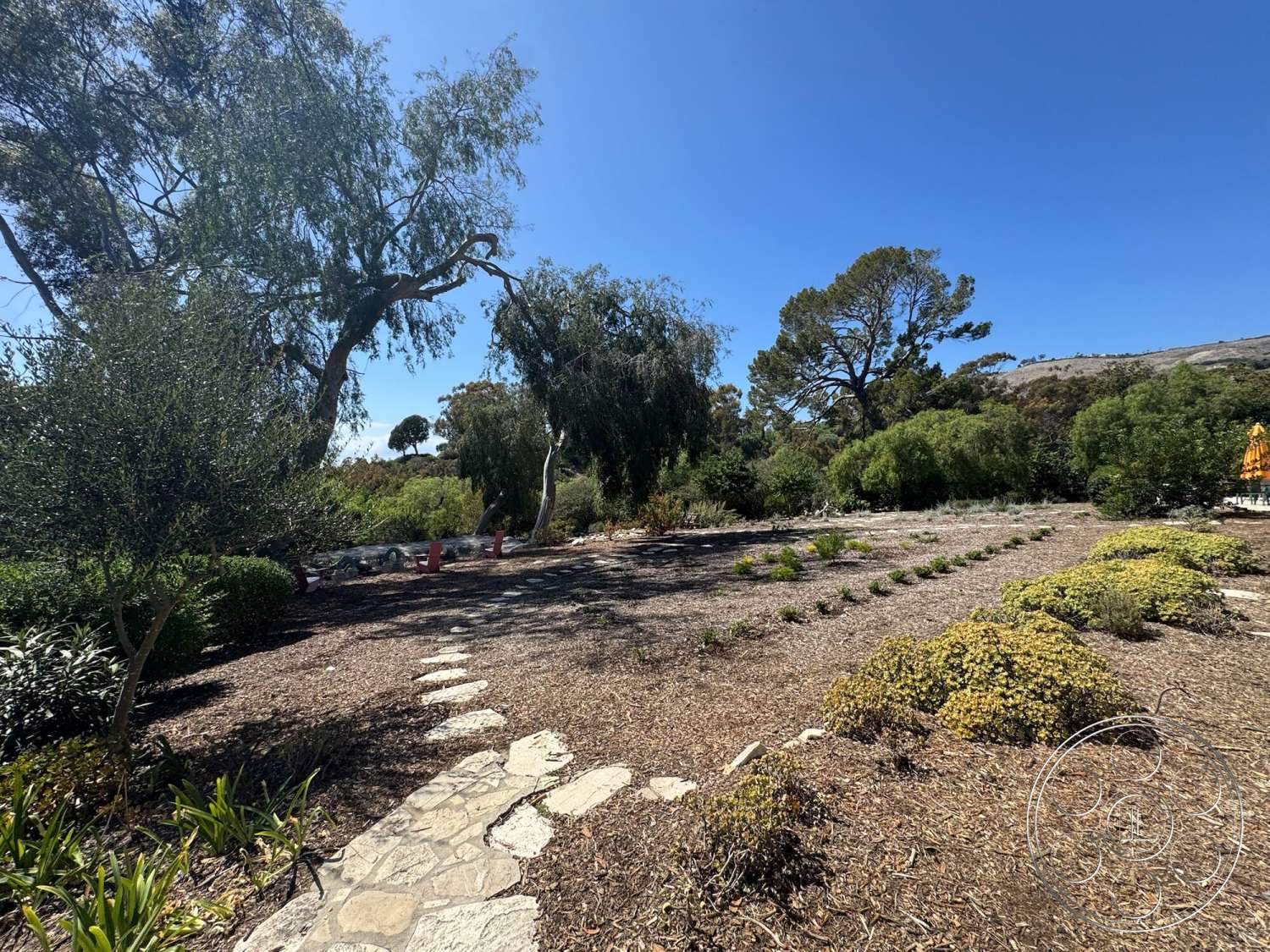 Farmstead Garden - exterior, mature trees, stone pathway, mountain backdrop, natural stone pavers, native shrubs, mulched flower beds, open sky view, landscape garden beds, decorative herb planting, planted vegetation