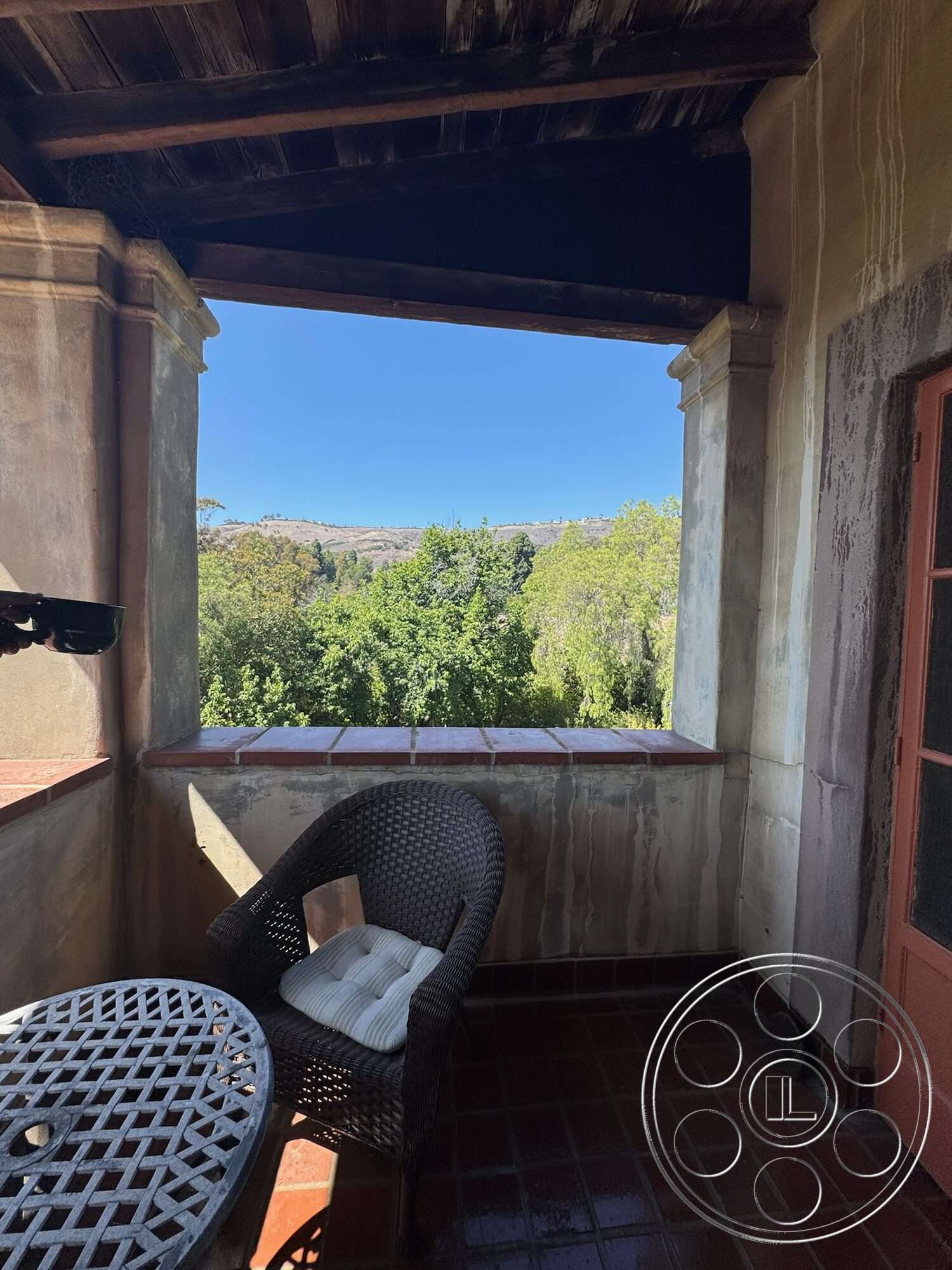 Farmstead Garden - natural light, exterior, balcony area, mountain view, arched doorway, terracotta tile flooring, stucco wall finish, wood beam ceiling, wrought iron table, woven wicker chair, red door accent