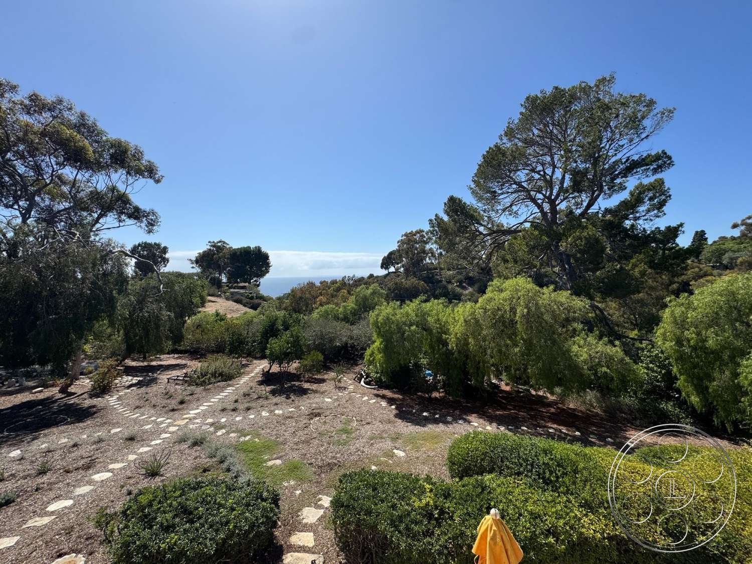 Farmstead Garden - landscaped garden, stone pathway, blue sky, deciduous trees, native vegetation, shrubbery, natural hillside setting, distant ocean view