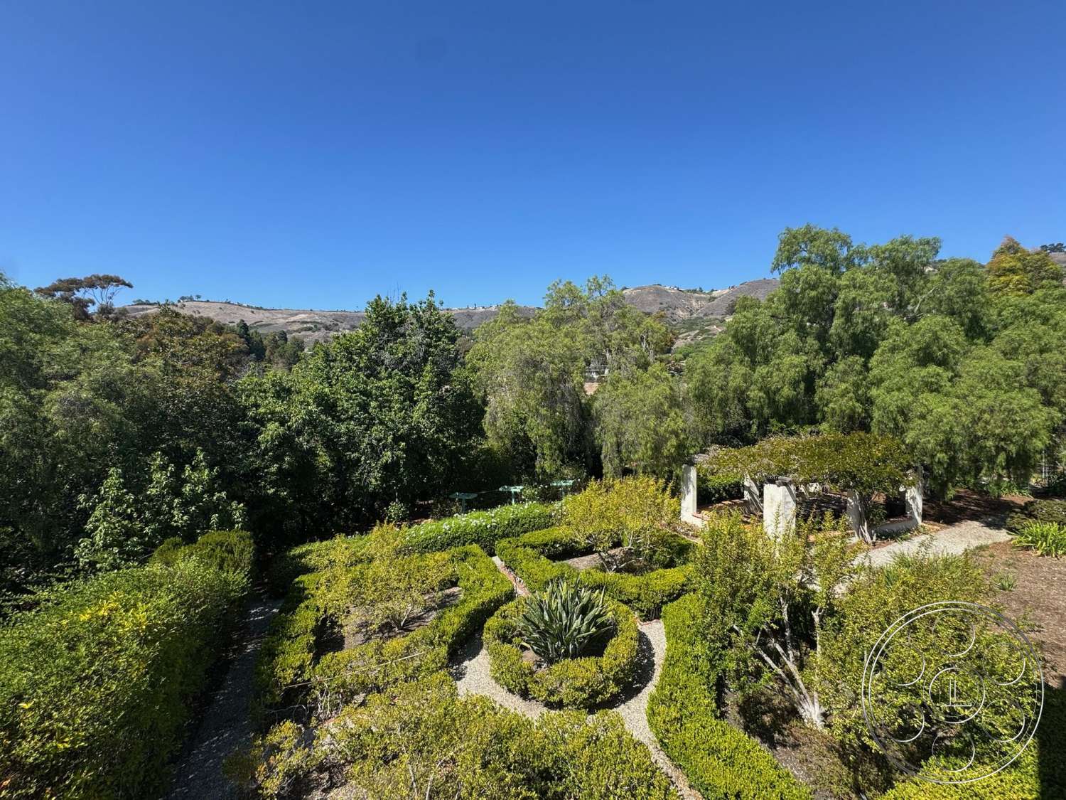 Farmstead Garden - exterior, lush greenery, patio area, mountain view, blue sky, textured foliage, open landscape, pergola structure, shrubbery garden beds, gravel garden paths, curved garden layout