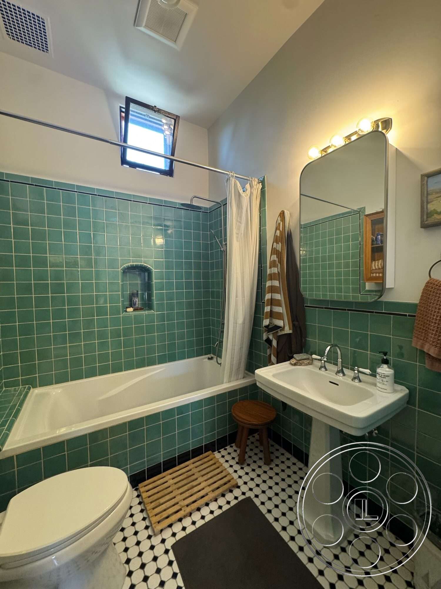 Farmstead Garden - window with wooden frame, white porcelain bathtub, black and white checkered tile flooring, framed bathroom mirror, green ceramic tile bathroom walls, white pedestal sink, chromed bathroom faucet, wooden bath mat, shower curtain rod