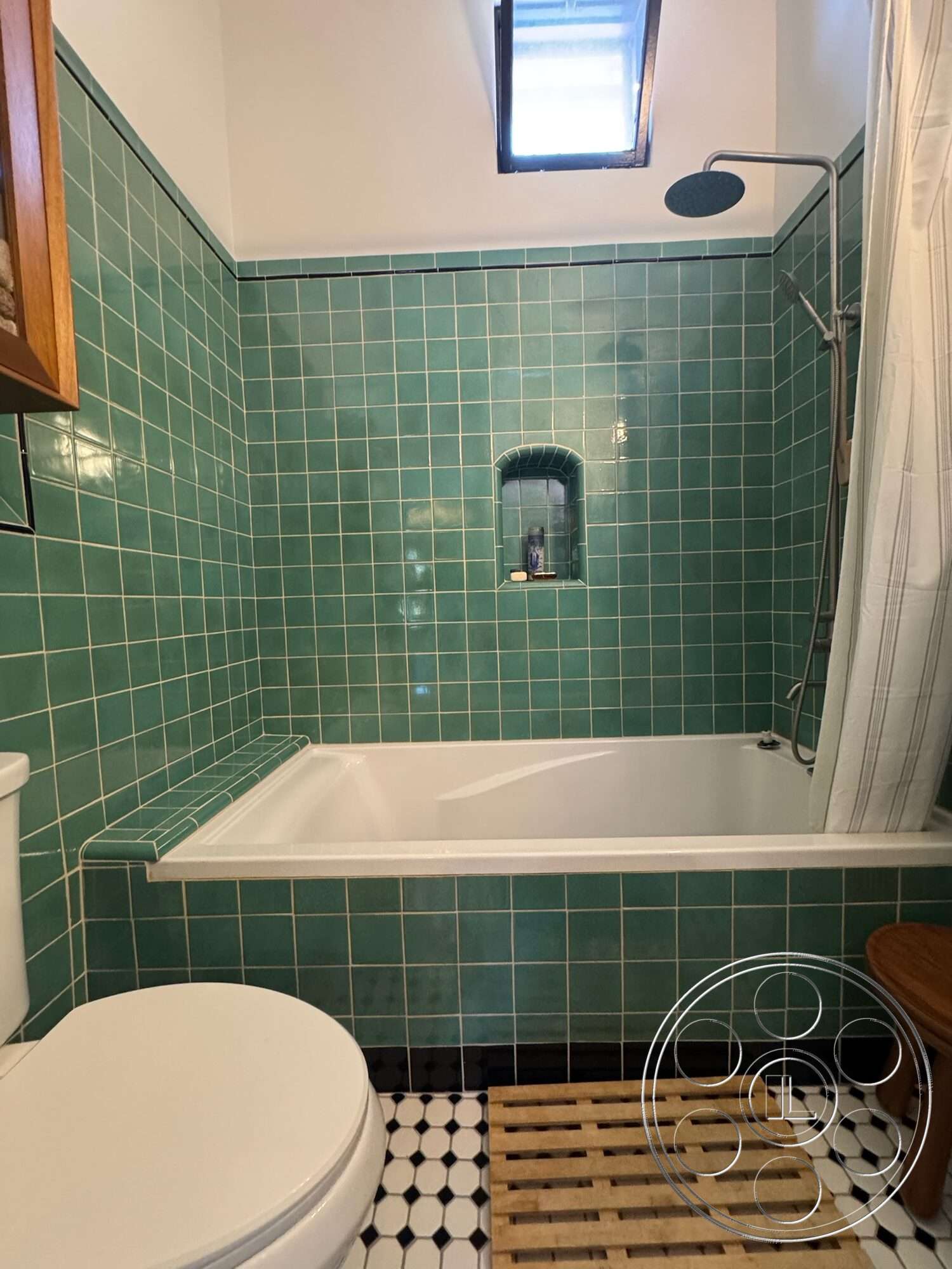 Farmstead Garden - exterior, white porcelain toilet, ceramic tile bathroom walls, glass shower head, black and white checkered tile flooring, acrylic bathtub, wooden slatted bath mat, niche shower shelf, skylight window