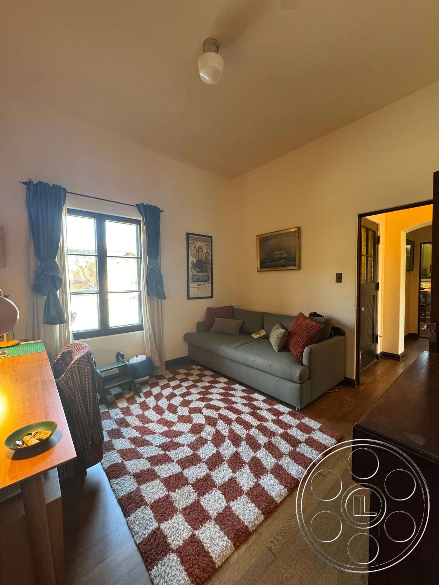 Farmstead Garden - textured area rug, decorative wall art, arched doorways, gray fabric sofa, wood window frames, striped throw pillows, hardwood floor living room, open room layout, modern ceiling light fixture, wood side table, white-painted walls, blue curtain drapes