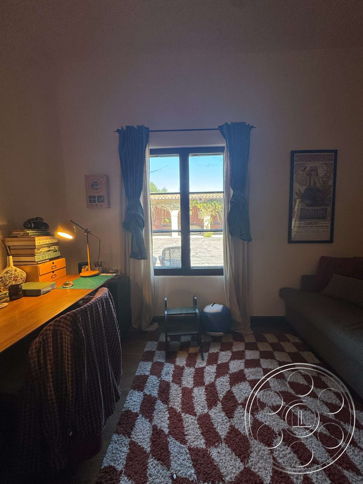 Farmstead Garden - natural light, textured area rug, framed wall art, hardwood floor, decorative wall panels, beige curtains, reading lamp, brown sofa, office workspace, wooden desk with storage drawers, large square window, home study area