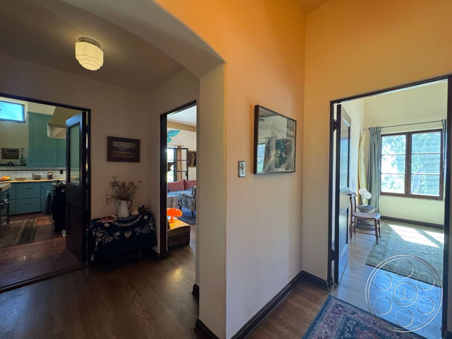Farmstead Garden - neutral color palette, natural light, kitchen view, light fixture, framed artwork, decorative table, seating area, decorative rug, hardwood floor, arched doorways, textured wall treatment, painted walls, interior hallway, window with drapes