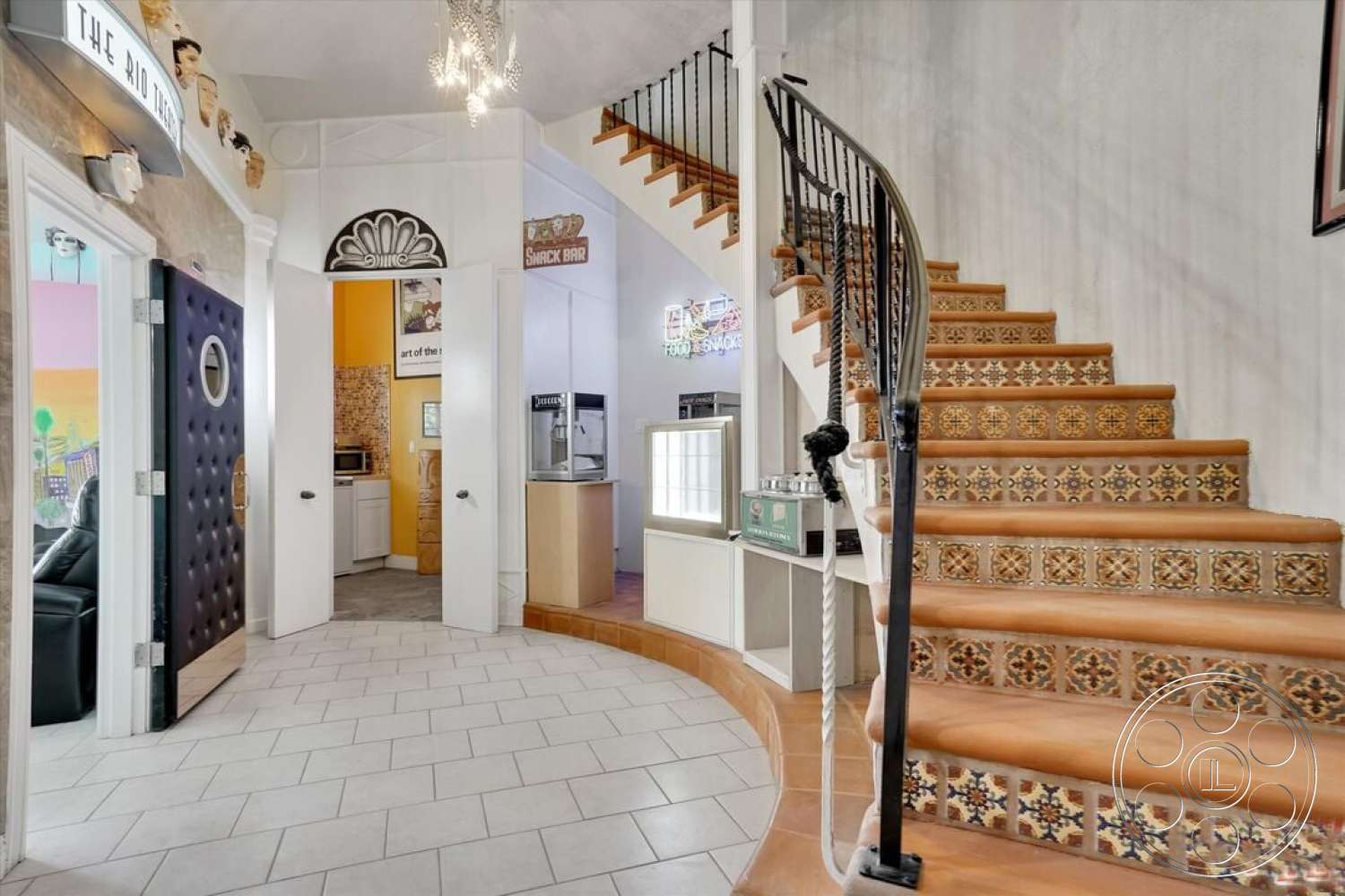 Spanish 170 - kitchenette area, arched doorway, colorful wall accents, hexagonal tile flooring, modern chandelier lighting, curved staircase design, exposed white plaster walls, classic crown molding, ornate staircase with decorative tile risers, black upholstered round door, cozy entryway, wood handrail on staircase