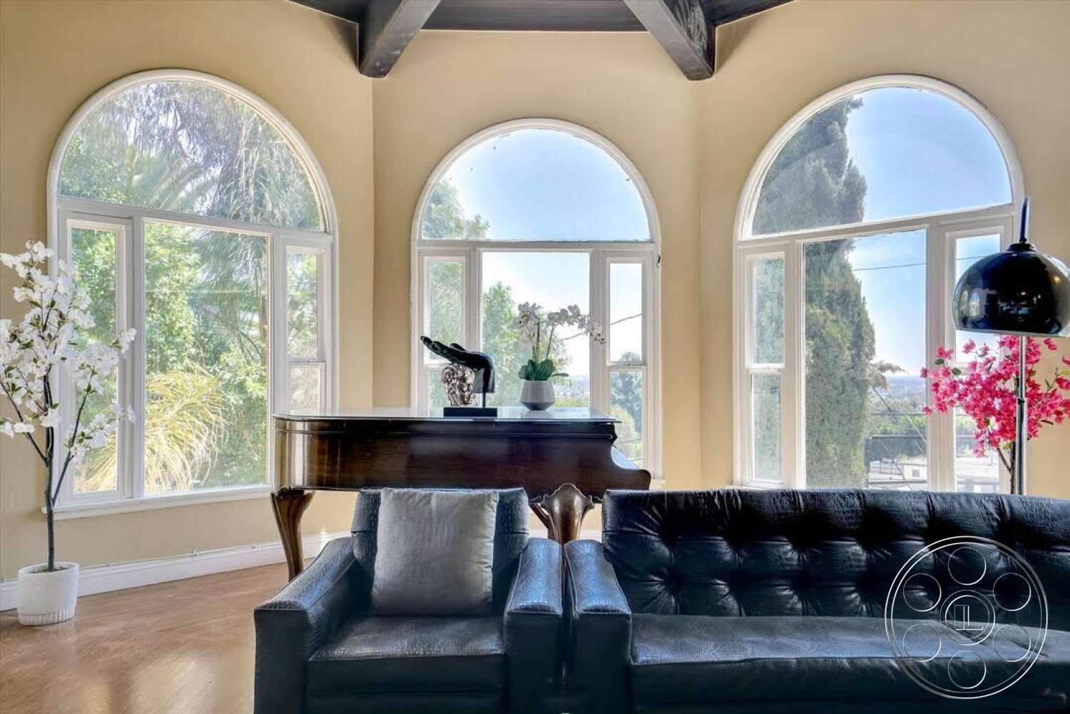 Spanish 170 - hardwood floor, arched windows, modern floor lamp, grand piano, exposed wood ceiling beams, large windows with views, leather tufted sofa, decorative flowering tree, potted orchid on piano