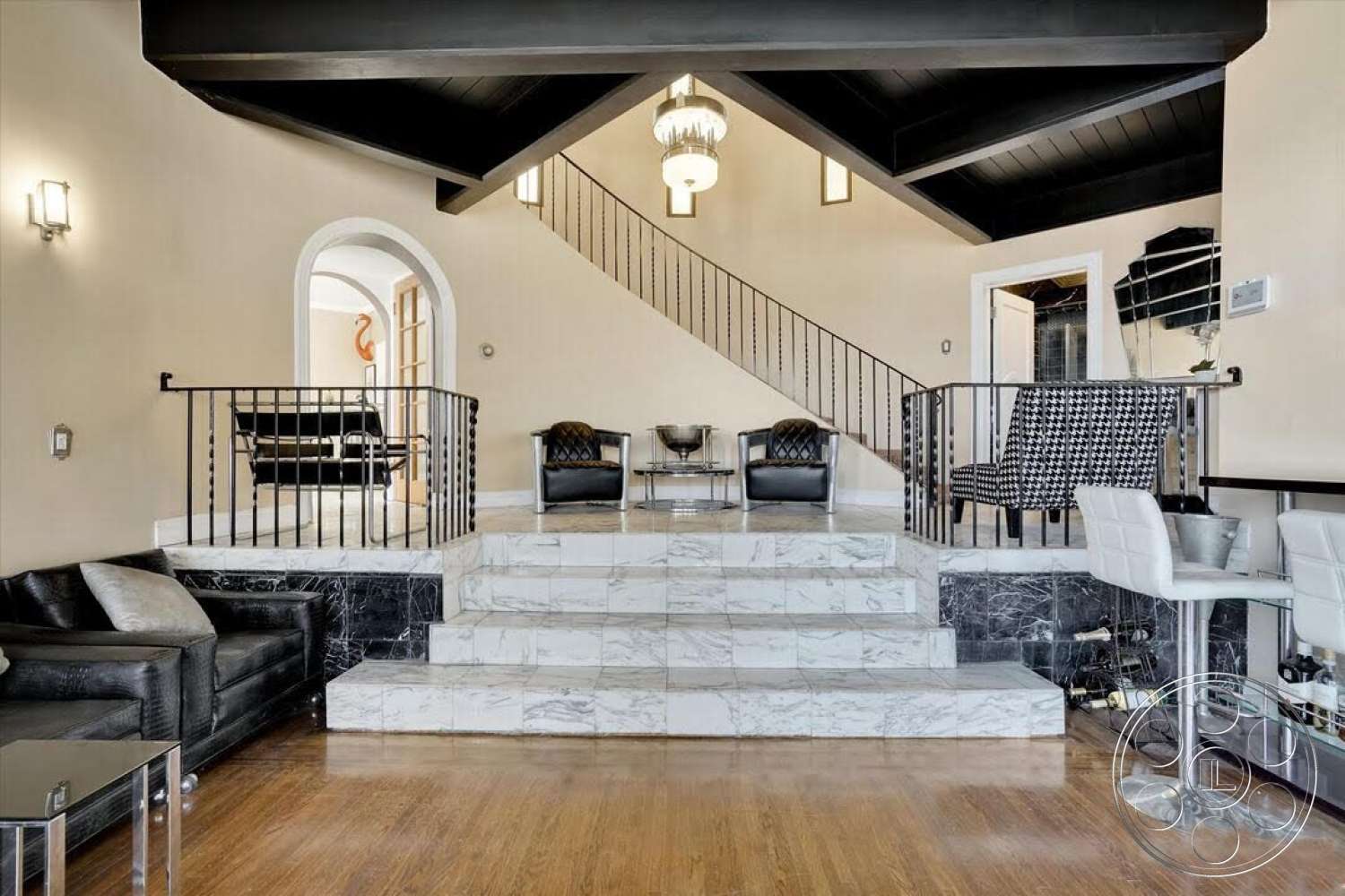 Spanish 170 - open floor plan, arched doorways, textured wall finishes, natural light from windows, modern chandelier, curved staircase, glass accent table, exposed wood ceiling beams, hardwood living room floors, marble steps, metal staircase railings, black marble base, plush leather seating, geometric patterned chairs