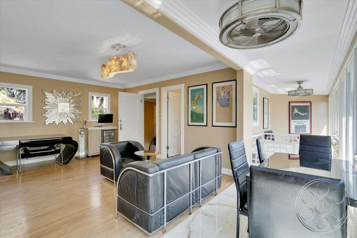 Spanish 170 - hardwood flooring, glass dining table, framed wall art, black leather chairs, exposed ceiling beams, modern light fixture, open concept living area, textured beige wall paint, mirrored accent wall