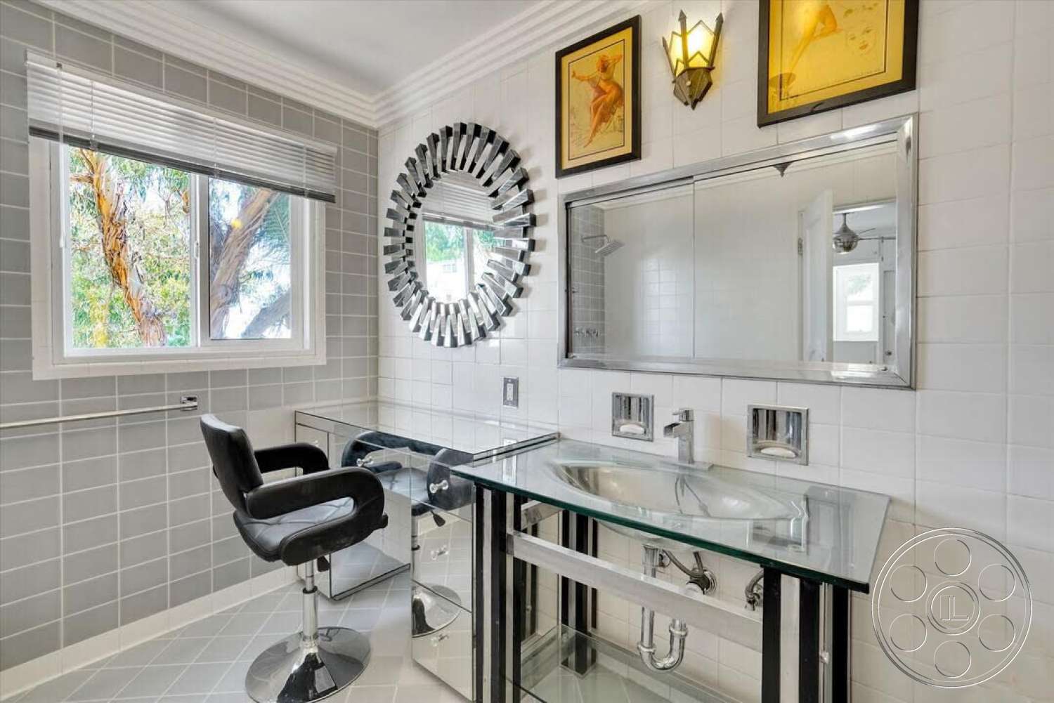 Spanish 170 - neutral color palette, minimalist bathroom design, white tile flooring, glossy white tile bathroom walls, square glass vanity top, chrome sink fixtures, modern round mirror with decorative border, chrome accent wall sconces, clear acrylic vanity chair, built-in wall mirror, window with white blinds