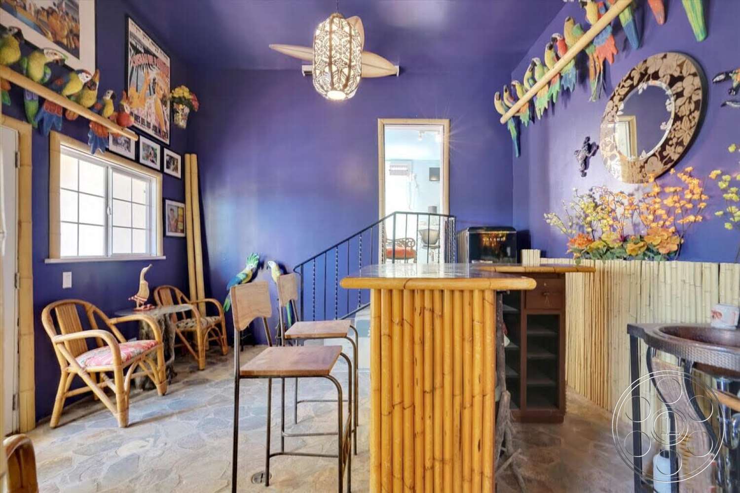 Spanish 170 - exterior, stone flooring, spiral staircase, wooden ceiling fan, wicker chairs, framed artwork on walls, purple accent walls, bamboo bar countertop, decorative tropical accents, hanging pendulum light