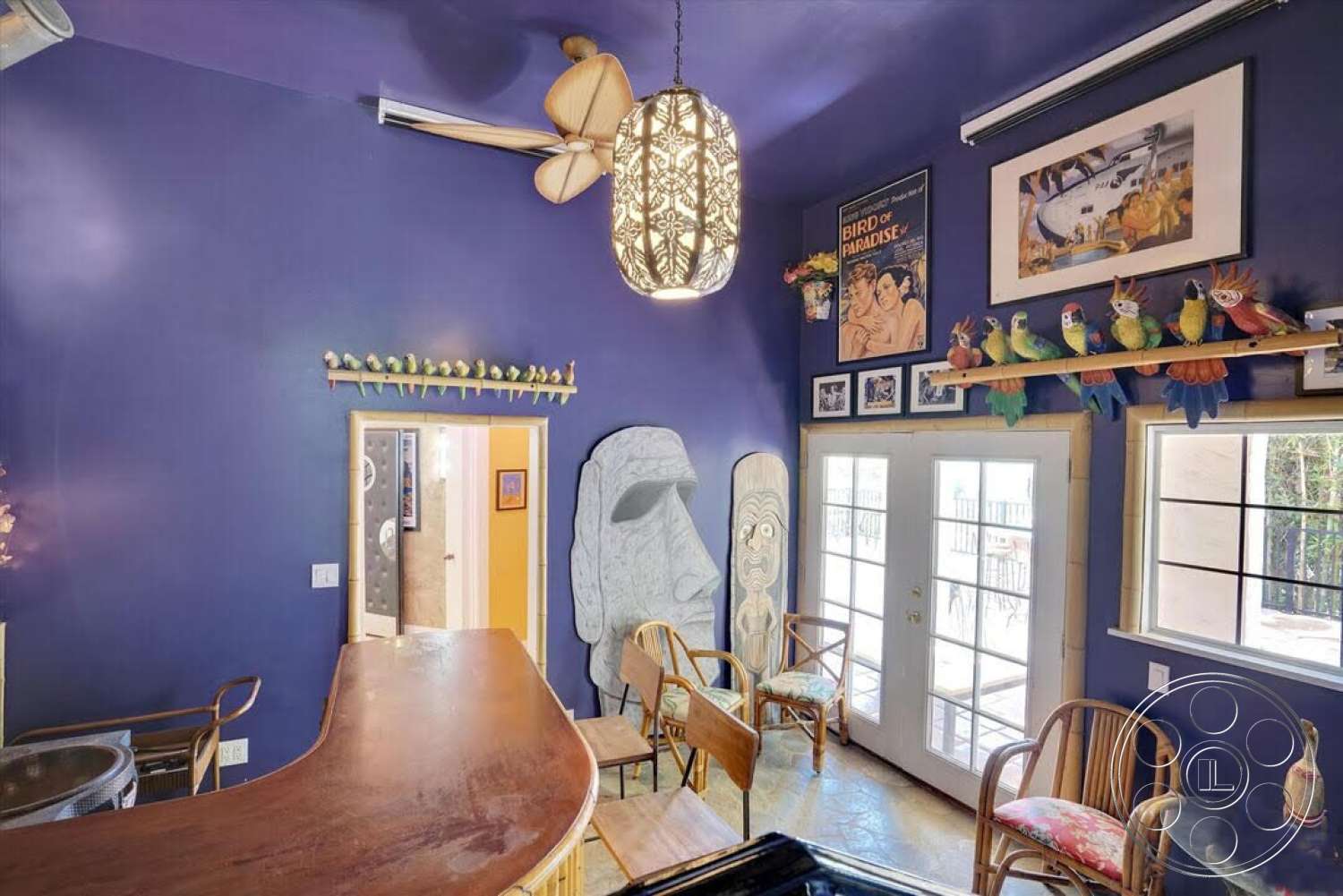 Spanish 170 - cozy seating area, wooden chairs, floor-to-ceiling windows, glass double doors, decorative wall hangings, wood bar counter, ornate ceiling light fixture, purple painted walls, faux tropical decor