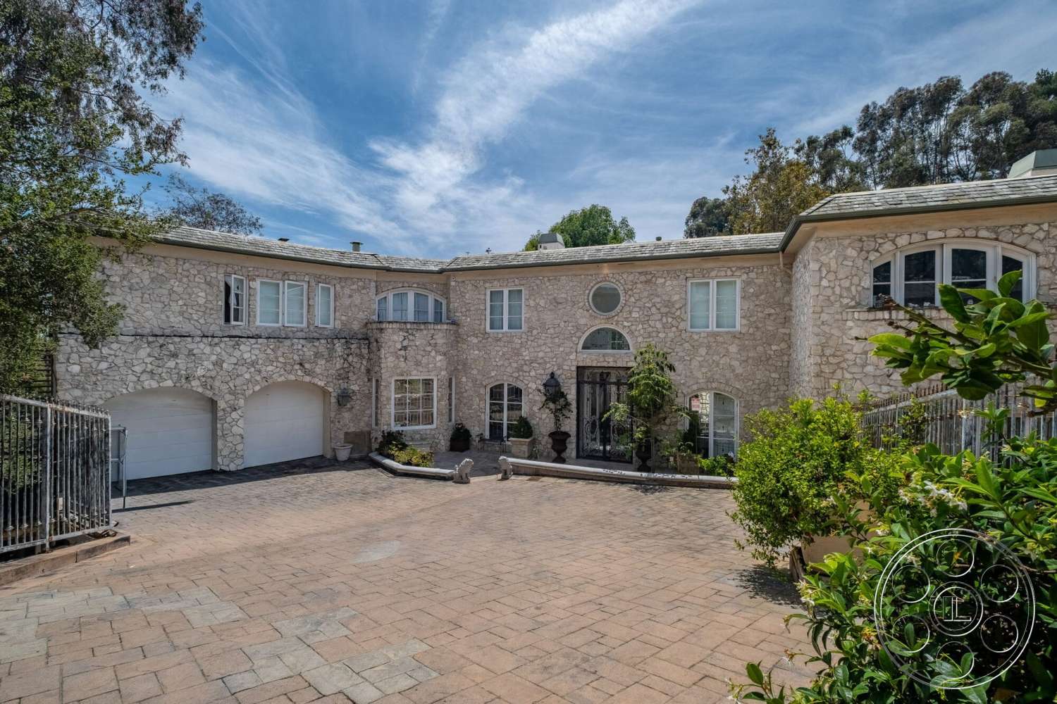 French 29 - exterior, arched entryway, outdoor light fixtures, flat roof design, landscaped garden area, stone facade walls, multi-pane windows, granite driveway pavers, detailed iron gate