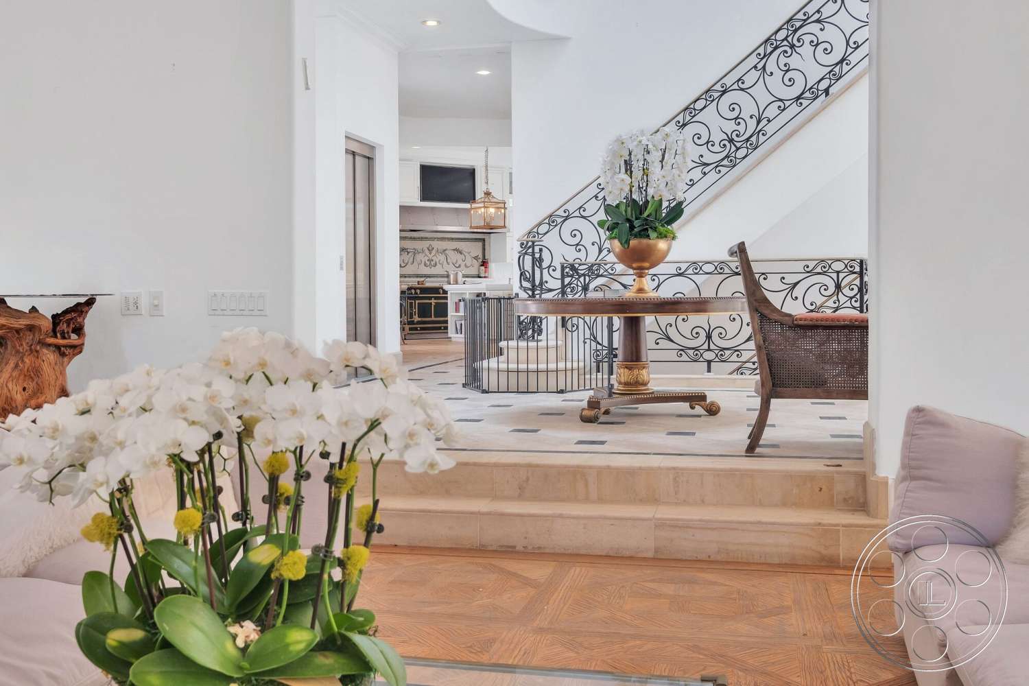 French 29 - hardwood flooring, recessed lighting, neutral upholstery, open kitchen layout, built-in kitchen cabinets, marble kitchen backsplash, white painted walls, decorative ceramic planter, parquet pattern wood floors, wrought iron staircase railing, stained wood table, green potted orchids
