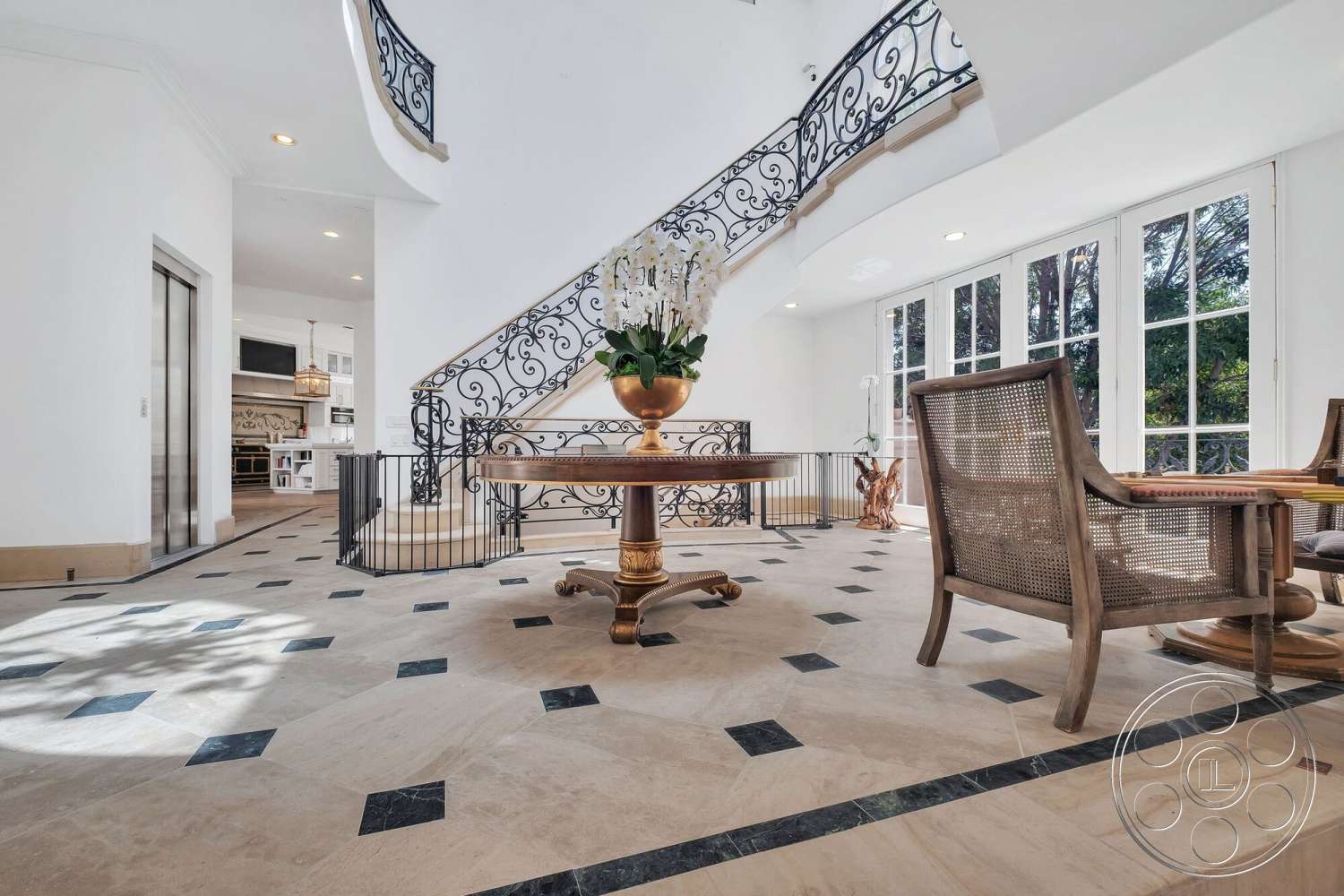 French 29 - open floor plan, wooden accent chairs, white painted walls, spiral staircase with wrought iron railing, elegant entryway design, natural light from floor-to-ceiling windows, marble tile flooring, black marble inlays, round dining table with decorative vase