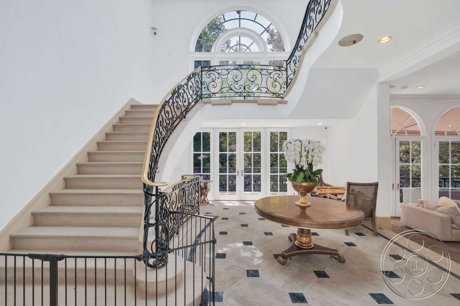 French 29 - open floor plan, floor-to-ceiling windows, spiral staircase, arched windows, elegant decor elements, luxurious entryway, white painted walls, natural light emphasis, exposed ceiling details, black and white checkered tile floor, light-colored marble flooring, wrought iron railing details, wooden round dining table