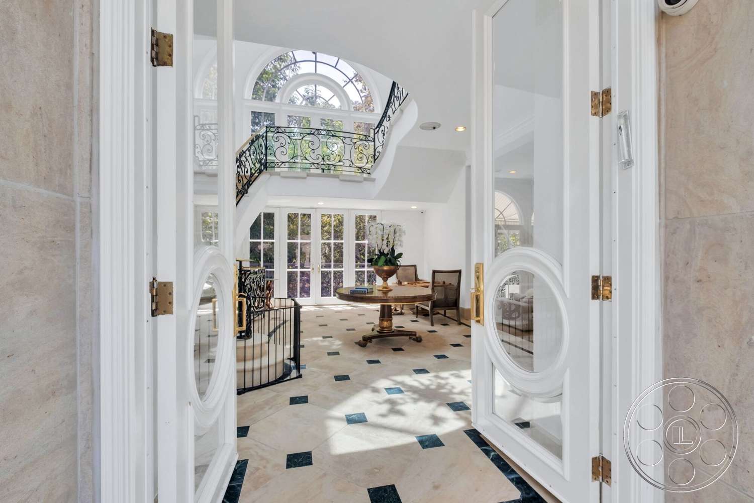 French 29 - floor-to-ceiling windows, elegant dining table, natural light flooding the space, decorative floral arrangement, crown molding details, curved staircase with wrought iron railing, marble entryway flooring, bright open concept layout, white double front doors, black and white checkered floor pattern, two-story foyer, rounded arch windows, exposed structural beams in ceiling