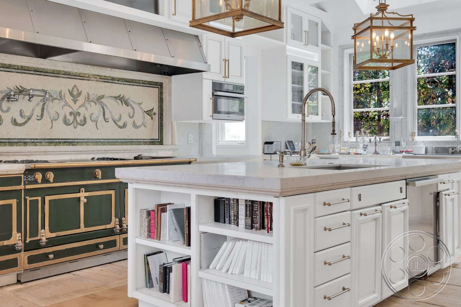 French 29 - natural light from large windows, marble kitchen countertops, stainless steel range hood, light beige tile flooring, open shelving with books and decor, custom green vintage gas range with gold accents, white cabinetry with glass fronts, mosaic tile backsplash with floral design, brass pendant lights