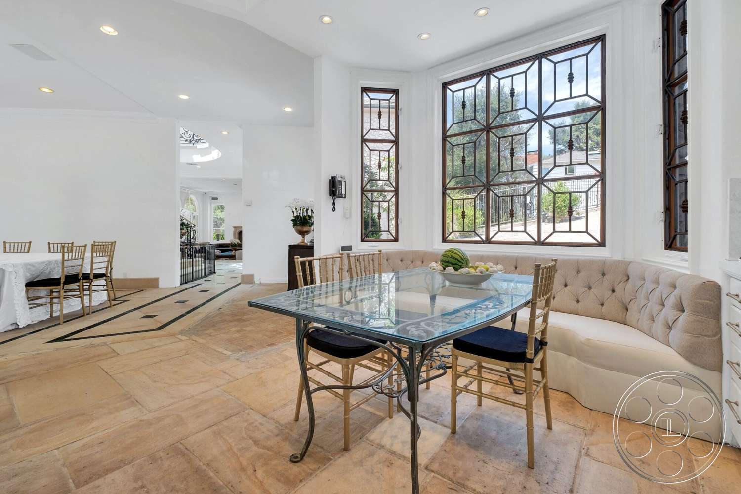 French 29 - natural light, open floor plan, interior space, textured stone flooring, white painted walls, high ceilings with recessed lighting, quartz kitchen countertop, built-in upholstered seating, custom glass dining table, tufted fabric banquette, gold-tone metal dining chairs, geometric stained glass windows, inviting dining area