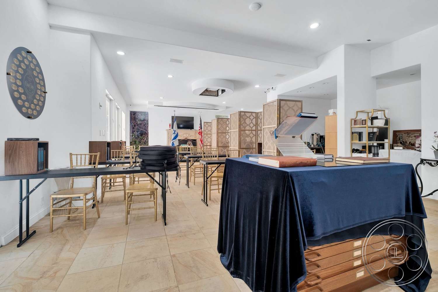 French 29 - minimalist decor, open floor plan, dark wood accents, natural stone flooring, flat ceiling, event space, bright ambient lighting, white painted walls, built-in shelving units, modern ceiling design, textured beige stone tiles, glass table with metal legs, folding wooden screen dividers, golden wooden chairs, function room layout