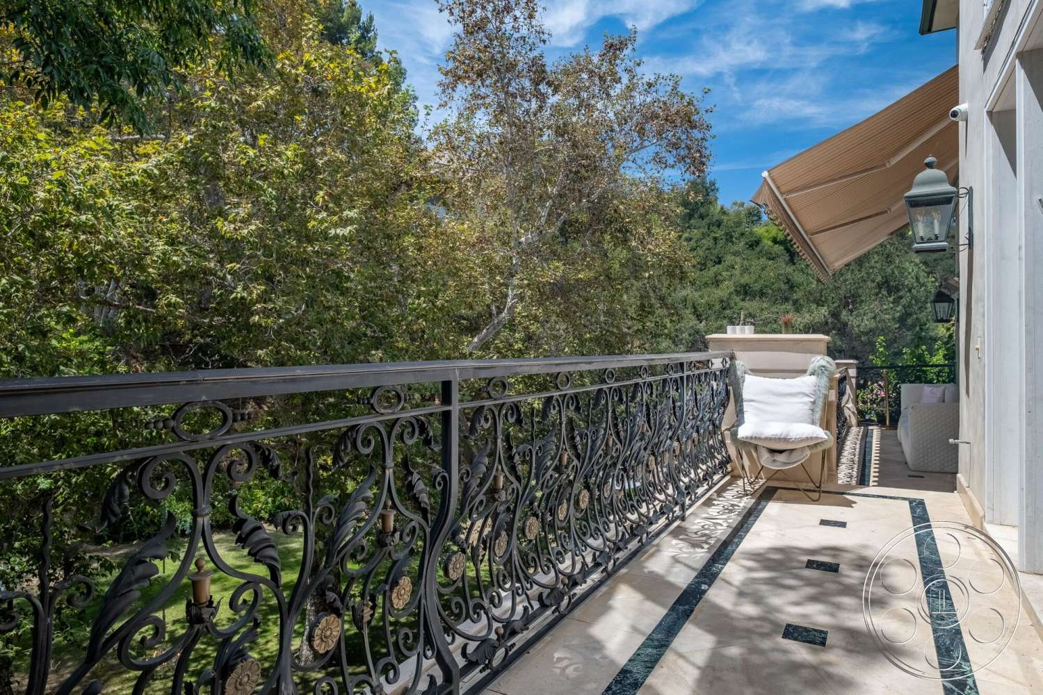 French 29 - exterior, outdoor lounge area, decorative lanterns, lush green trees, wrought iron balcony railing, woodland setting, stone balcony flooring, elegantly shaped balcony, large awning