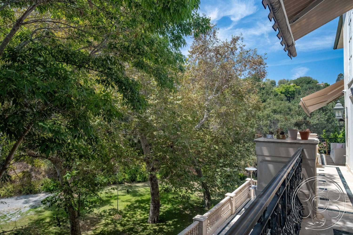French 29 - exterior, gravel pathway, landscaped lawn, lush foliage, textured plaster walls, shade from trees, hillside location, wooden planters, outdoor garden view, decorative outdoor light fixtures, balcony railing, stone railing details, tiled balcony flooring