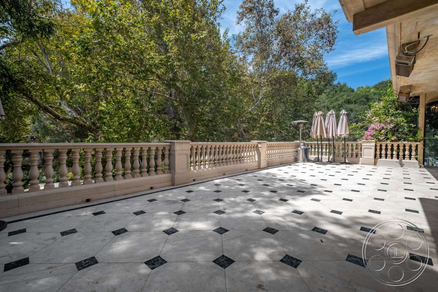 French 29 - natural light, exterior, surrounding greenery, outdoor patio area, ground-level terrace, patterned marble patio flooring, octagonal marble pavers with black granite inlays, ornate stone balustrade railing, dual market umbrellas