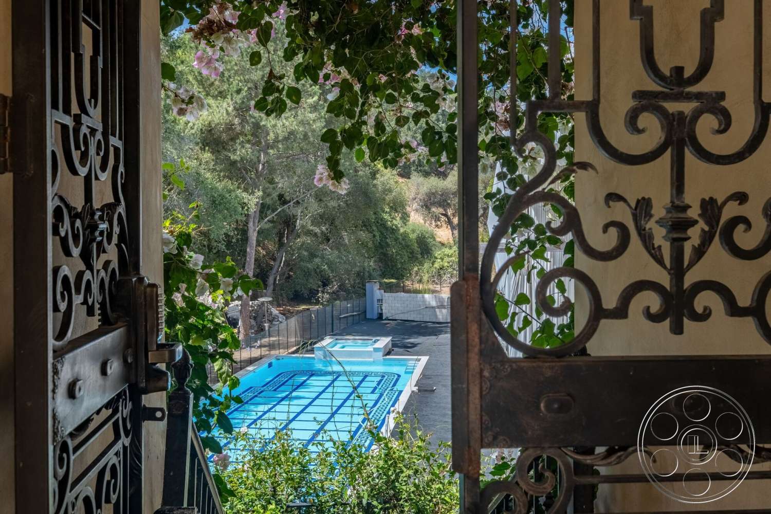 French 29 - exterior view, rectangular swimming pool, ornate iron gate, sunny outdoor setting, tile pool decking, brick boundary wall, surrounding landscape with greenery