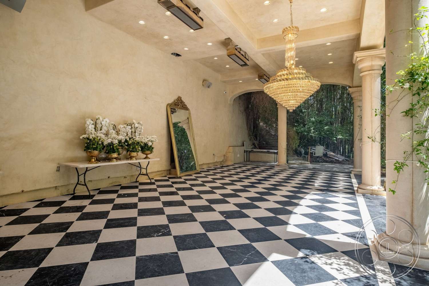 French 29 - textured plaster walls, ambient recessed lighting, chandelier lighting fixture, decorative flower arrangements, black and white checkered tile floors, ornate decorative mirror, column support structures