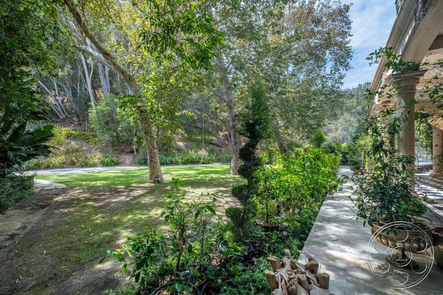French 29 - exterior, landscaped garden, lush greenery, mature trees, stone pathway, grassy lawn, decorative planters, tall hedges, sunlit outdoor space, ground cover plants