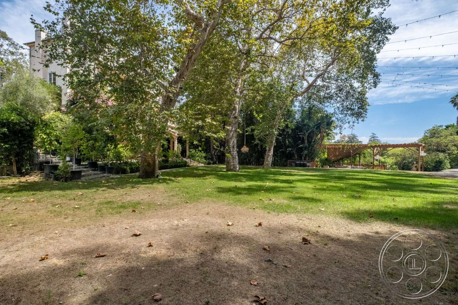 French 29 - exterior, outdoor seating area, stone pathway, lush green lawn, decorative string lights, wooden pergola, suburban backyard, mature shade trees, landscape garden bed, multi-level garden terrace