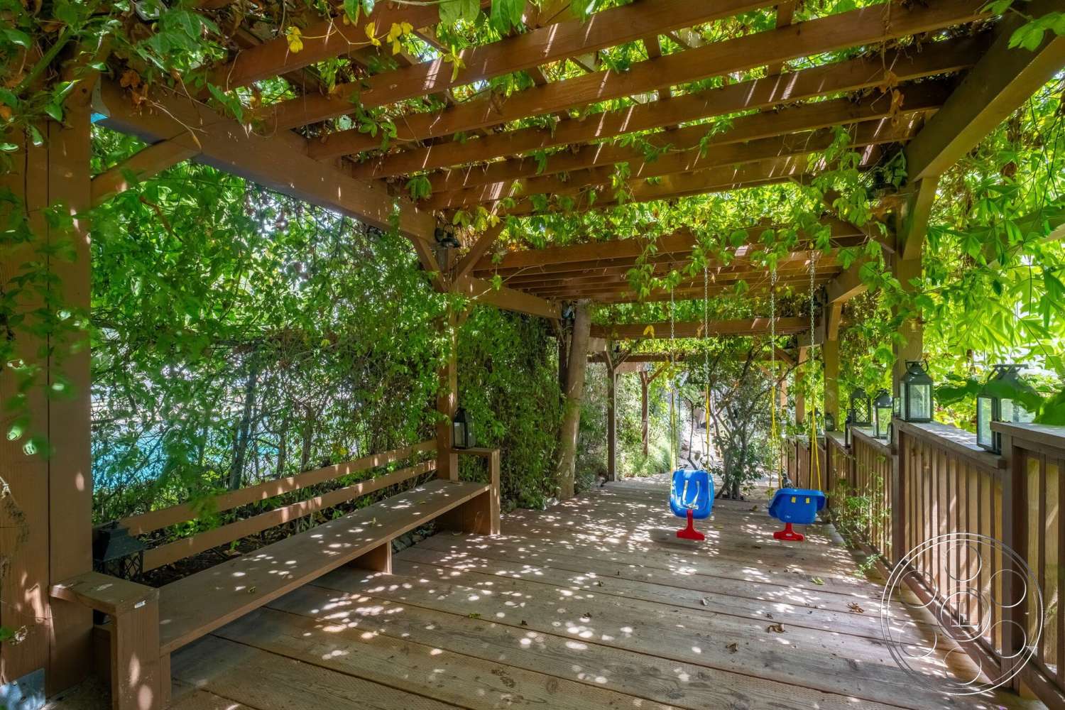 French 29 - outdoor seating area, wooden bench seating, wooden deck flooring, wood pergola structure, interior outdoor space, swing seat elements, greenery climbing plants, natural light filtering, surrounding garden environment