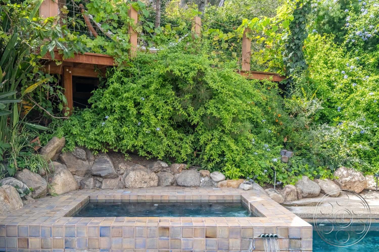 French 29 - exterior, brick pathway, natural stone retaining wall, lush greenery landscape, tropical garden setting, multi-level outdoor space, rectangular hot tub, tile spa surround, wooden deck structure, cascading water features