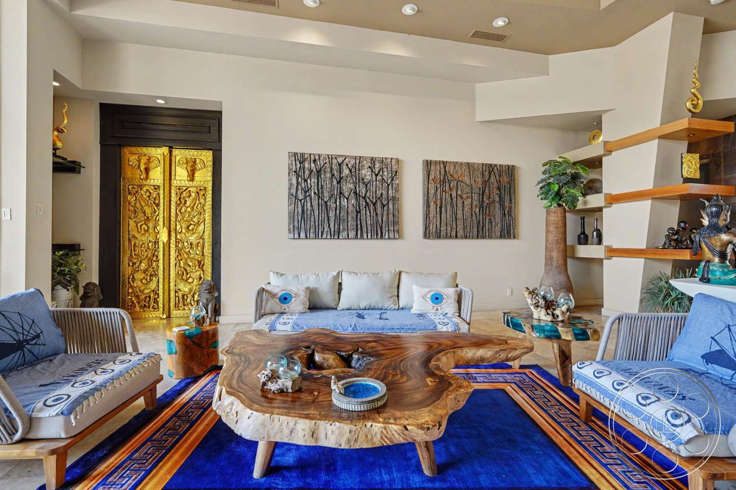 Rancho Mirage 4 - indoor plants, light-colored walls, recessed ceiling lights, natural wood accent wall, modern interior design, exposed wood shelving, beige upholstered sofa, ceramic decorative vases, blue area rug, handcrafted wood coffee table, blue decorative throw pillows, golden decorative double doors, textured wall art panels