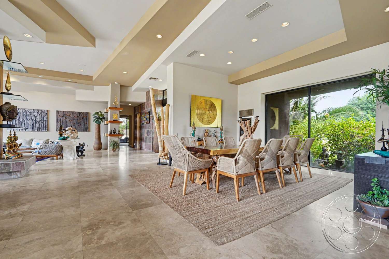 Rancho Mirage 4 - neutral color palette, large glass sliding doors, natural wood dining table, polished marble flooring, contemporary dining area, woven dining chairs, textured ceiling details, area rug under dining table, high ceiling with recessed lighting, open concept living area, built-in shelving units, artwork wall displays, indoor plants and greenery, modern decorative sculptures