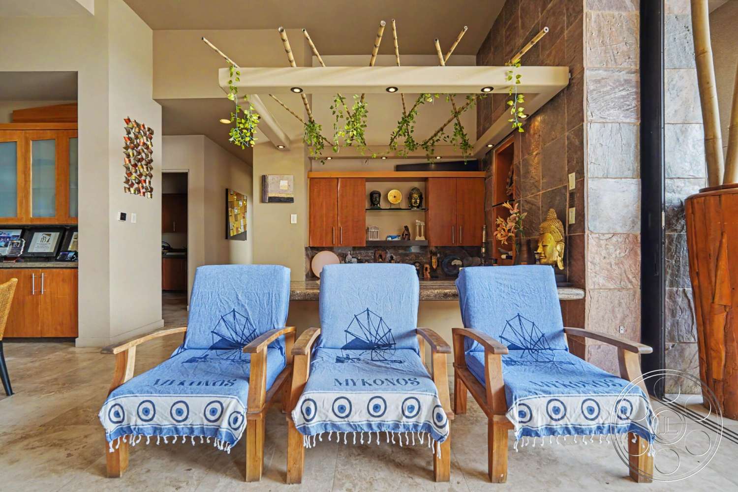 Rancho Mirage 4 - decorative wall art, exposed ceiling beams, modern bar area, recessed lighting fixtures, wooden kitchen cabinets, neutral painted walls, open concept living area, natural stone wall cladding, beige marble floor tiles, textile lounge chair covers, bamboo accent decor, kitchen island with counter stools