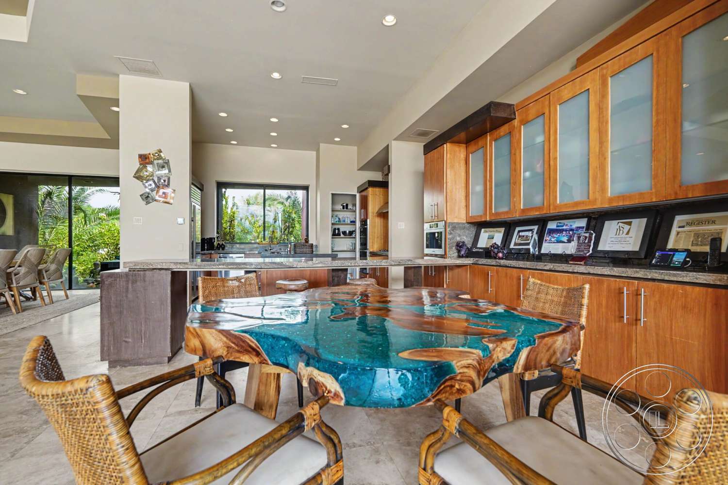 Rancho Mirage 4 - natural light, tile flooring, minimalist design, open floor plan, large glass windows, exposed ceiling, lush outdoor view, modern bar stools, granite kitchen countertops, light hardwood cabinetry, contemporary kitchen cabinets, wood table with epoxy resin inlay, woven rattan chair details, decorative wall photos