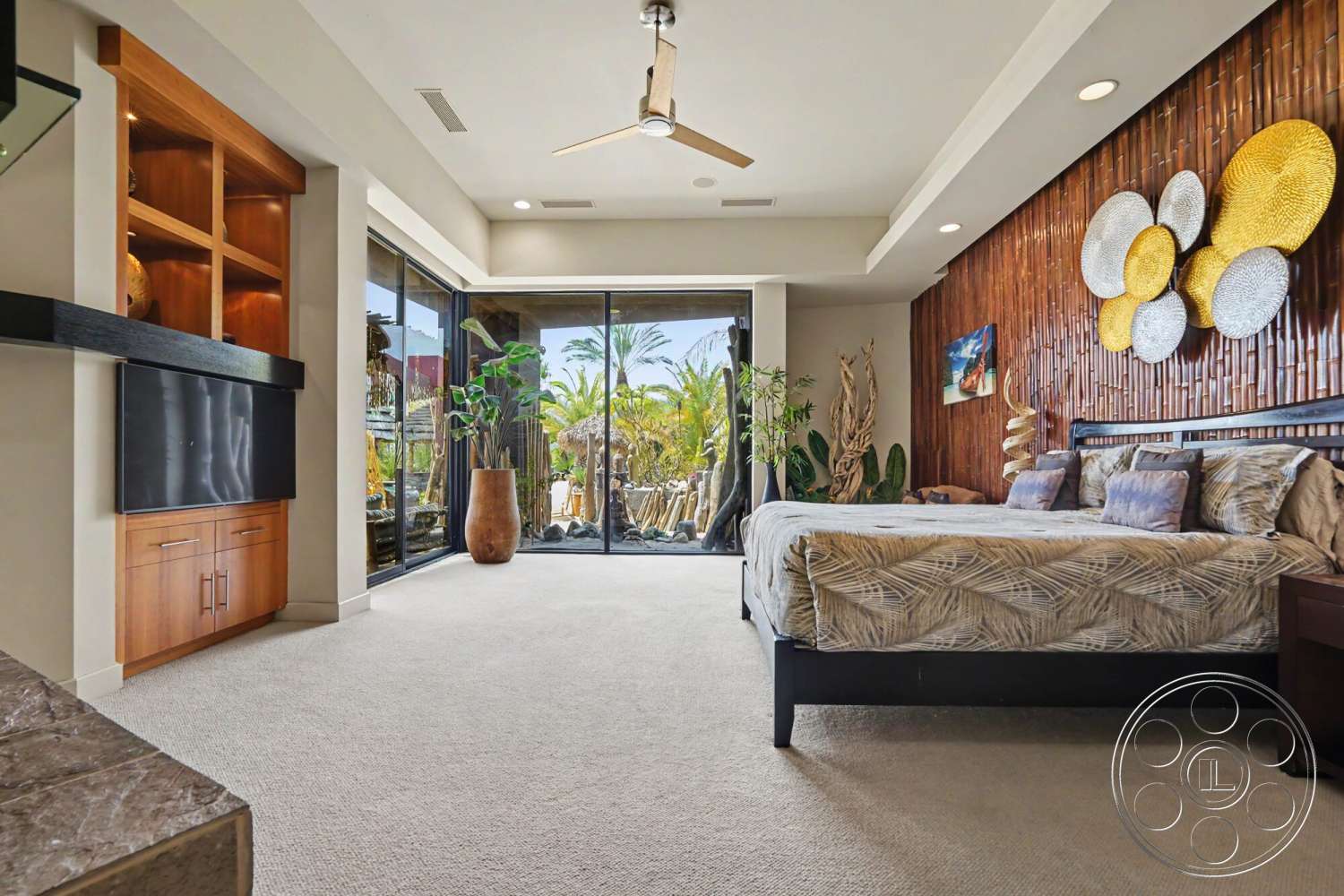 Rancho Mirage 4 - floor-to-ceiling windows, wood accent wall, textured wall decor, modern ceiling fan, potted indoor plants, natural light ambiance, carpet bedroom flooring, built-in wooden cabinetry