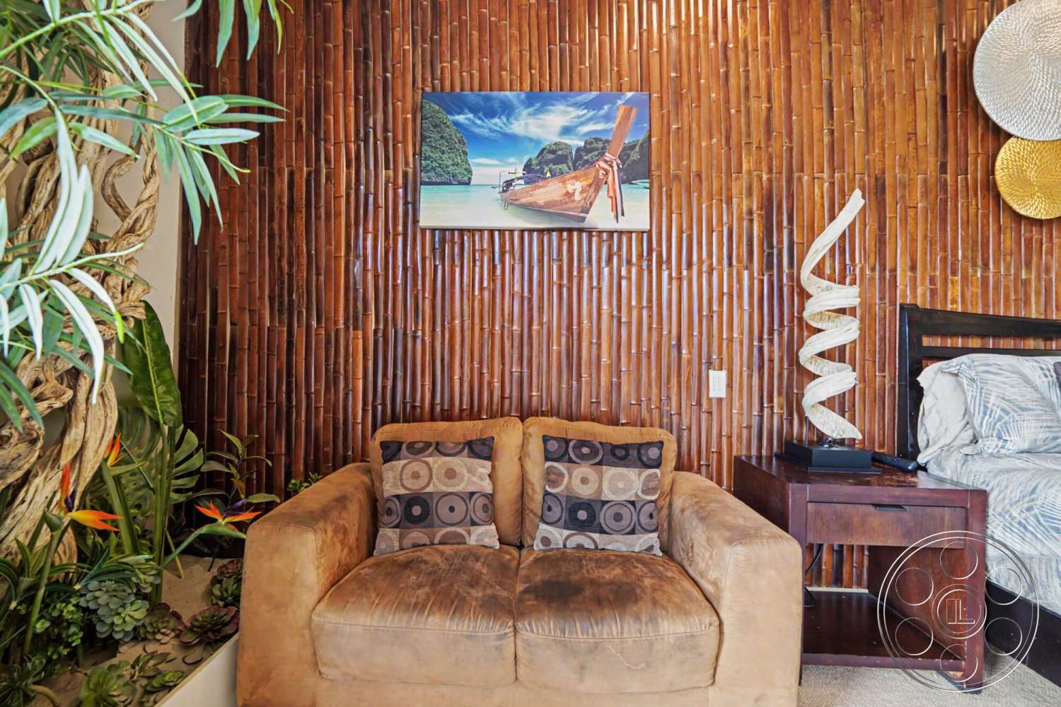 Rancho Mirage 4 - textured wall art, tan leather armchair, dark wood nightstand, bamboo accent wall, tropical plant decor, uplight sculpture, round patterned throw pillows, artistic woven wall decor, sand-colored carpet flooring