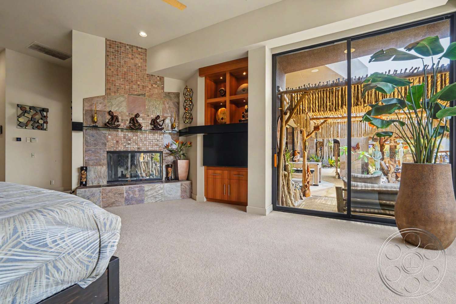 Rancho Mirage 4 - natural light, decorative sculptures, cozy living space, textured wall decor, open floor plan design, potted indoor plants, floor-to-ceiling glass doors, natural stone fireplace surround, carpet bedroom flooring, built-in wooden cabinetry, slate stone feature wall