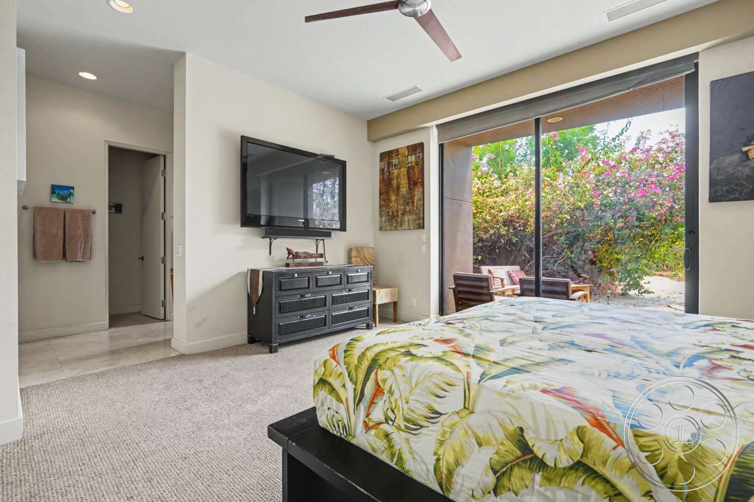 Rancho Mirage 4 - neutral color palette, artwork on walls, textured wall finish, built-in entertainment center, comfortable seating area, modern ceiling fan, outdoor garden view, floor-to-ceiling glass doors, carpet bedroom flooring