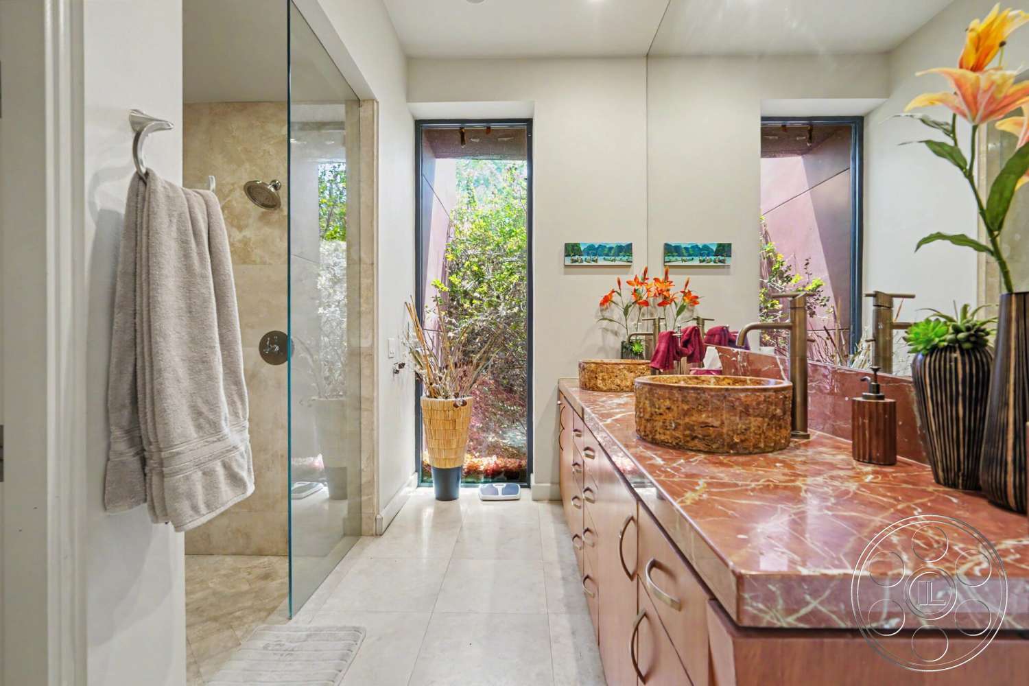 Rancho Mirage 4 - stone accent wall, glass shower enclosure, integrated planters with greenery, natural light from floor-to-ceiling windows, large format tile flooring, marble bathroom countertop, custom wood cabinetry, textured tile shower walls, decorative vase with floral arrangement, modern fixtures and faucets, soft towel hanging rack
