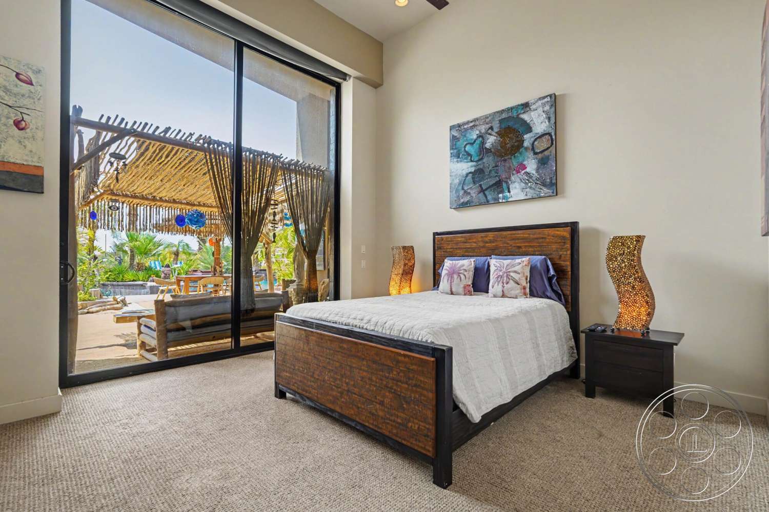 Rancho Mirage 4 - textured wall art, outdoor patio view, floor-to-ceiling glass doors, carpet bedroom flooring, beach house setting, king-size wooden bed frame, decorative bedside lamps
