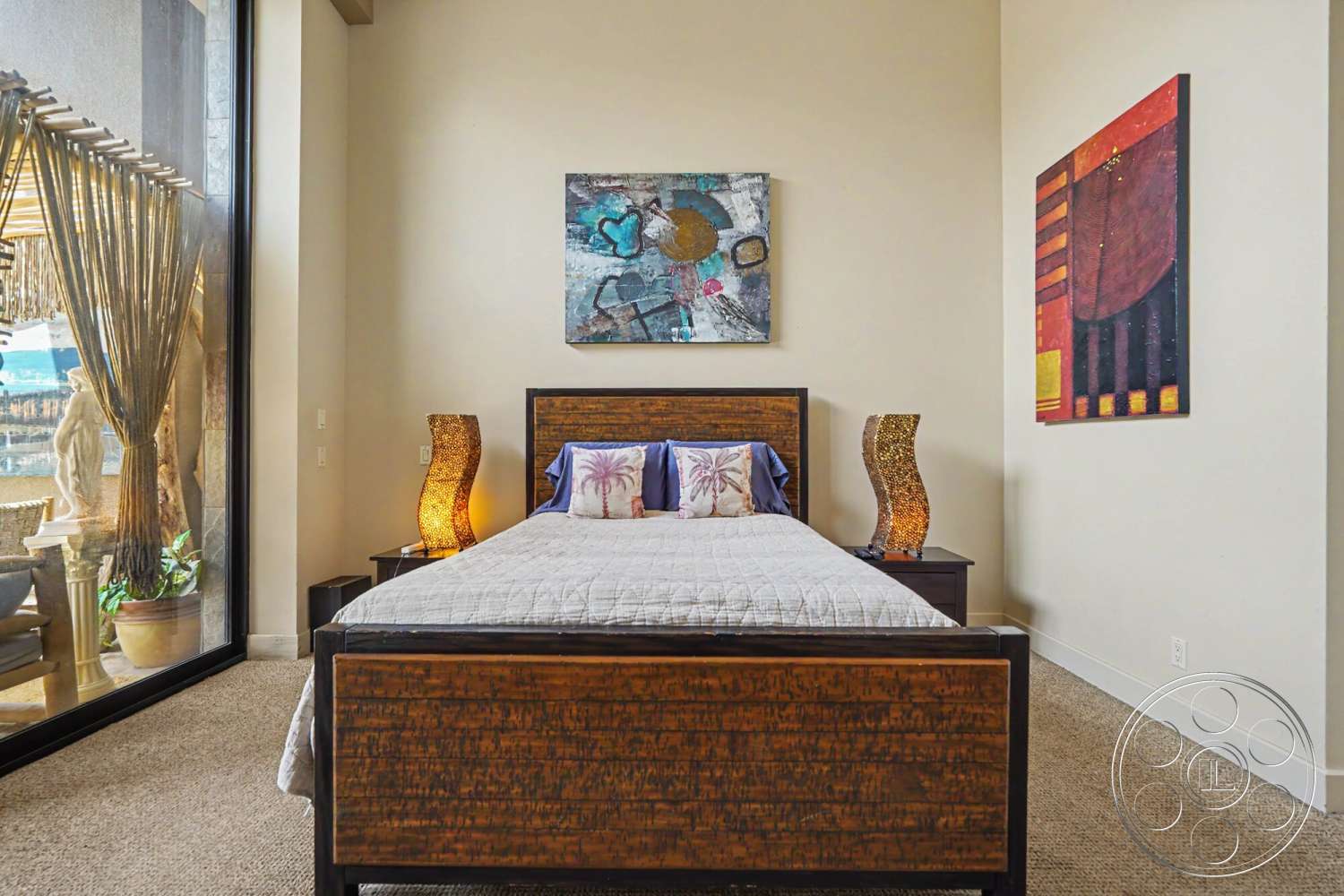 Rancho Mirage 4 - abstract wall art, floor-to-ceiling windows, textured plaster walls, cozy bedroom, decorative table lamp, carpet bedroom flooring, modern decorative accents, wood bed frame with patterned headboard