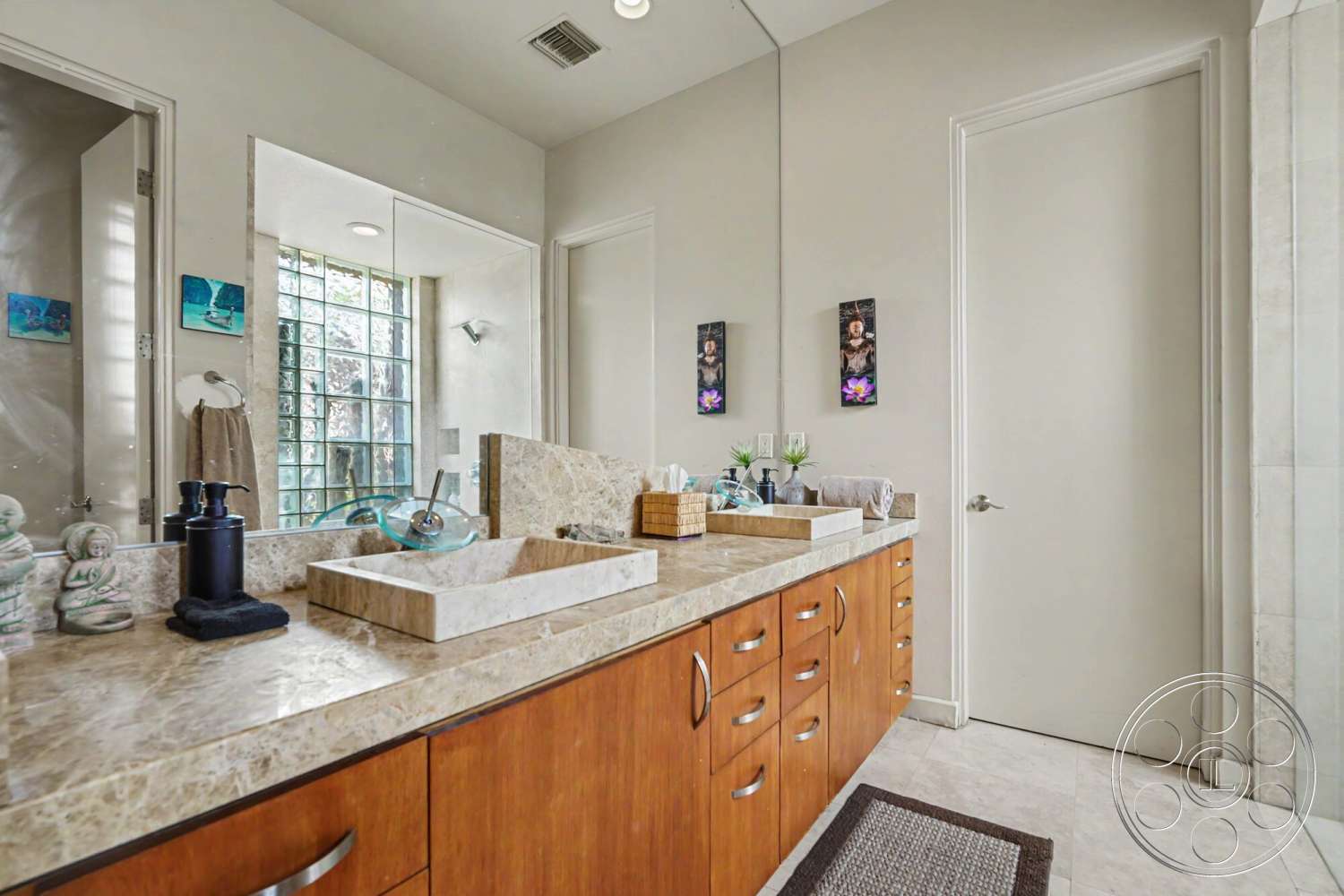 Rancho Mirage 4 - minimalist decor, neutral color palette, modern lighting fixtures, textured plaster walls, tile bathroom flooring, marble bathroom countertop, functional bathroom layout, mirrored wall above vanity, vanity with wood cabinetry, glass block shower wall, stone sink basin