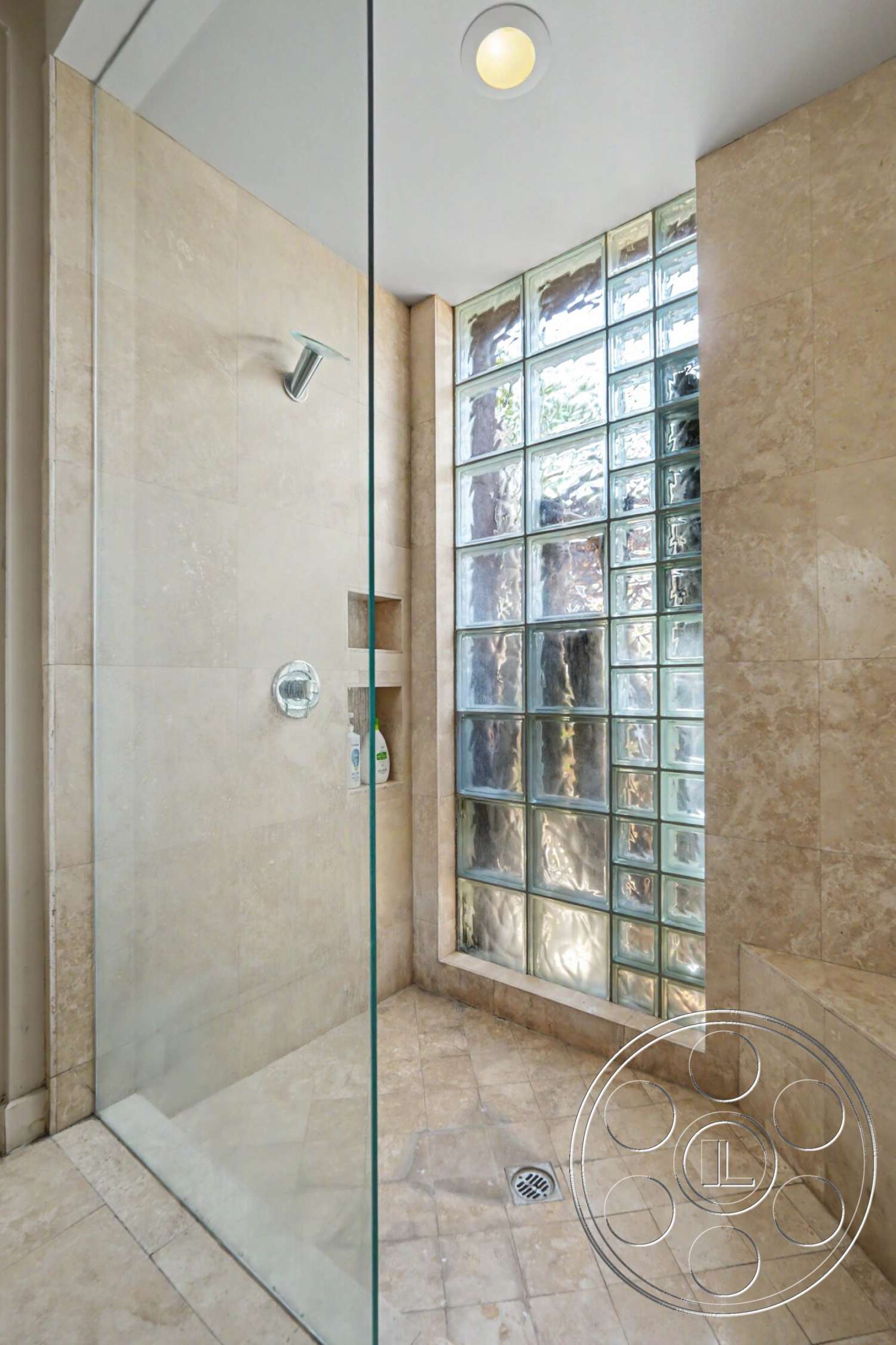 Rancho Mirage 4 - textured stone walls, glass block wall, glass shower doors, recessed ceiling lighting, modern bathroom interior, stone tile shower flooring, corner shower design, shower niche shelving