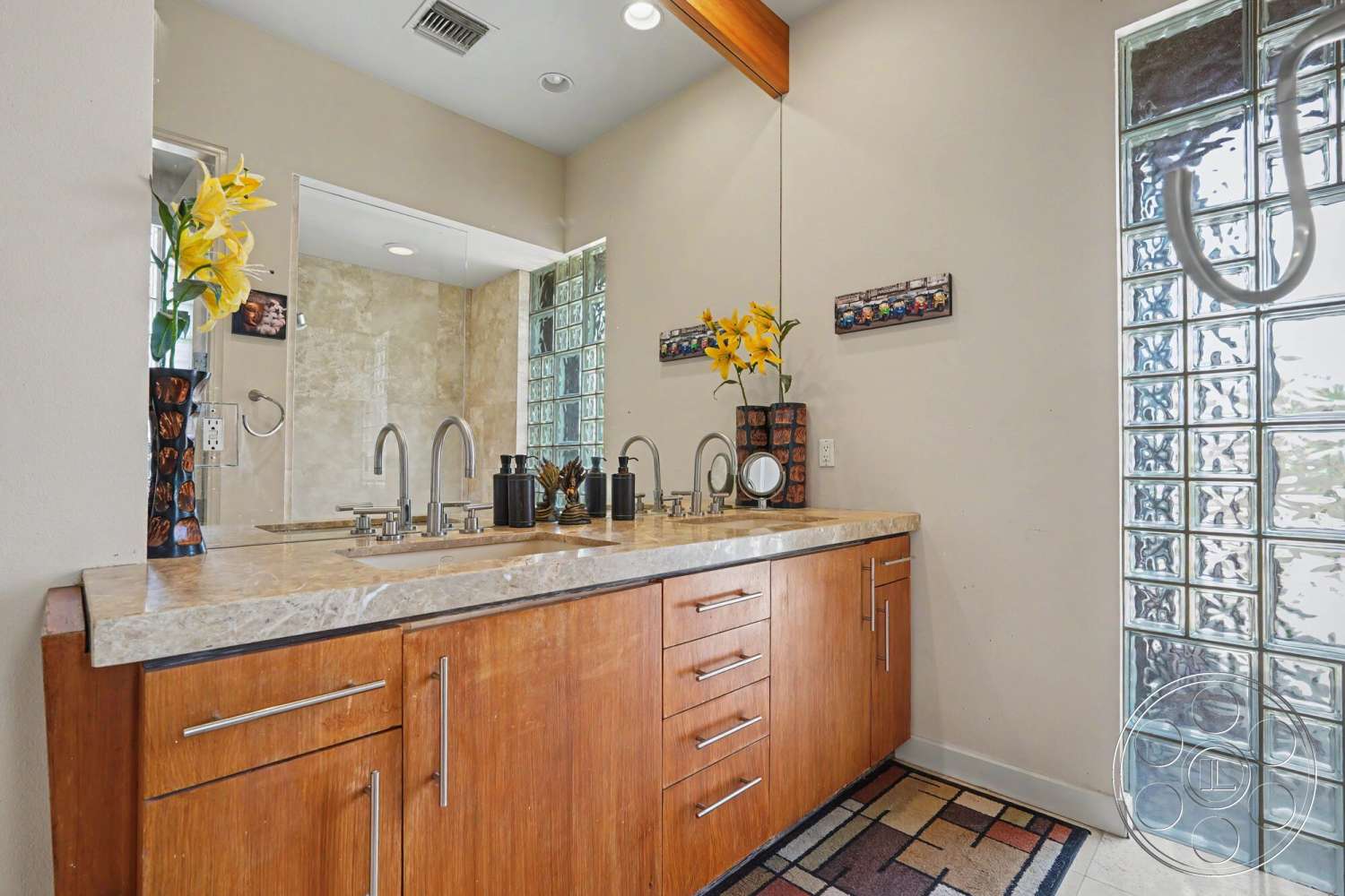 Rancho Mirage 4 - textured wall finish, recessed ceiling lights, glass block wall, tile bathroom flooring, marble bathroom countertop, modern plumbing fixtures, wood vanity cabinets, bright floral accents, mounted mirror