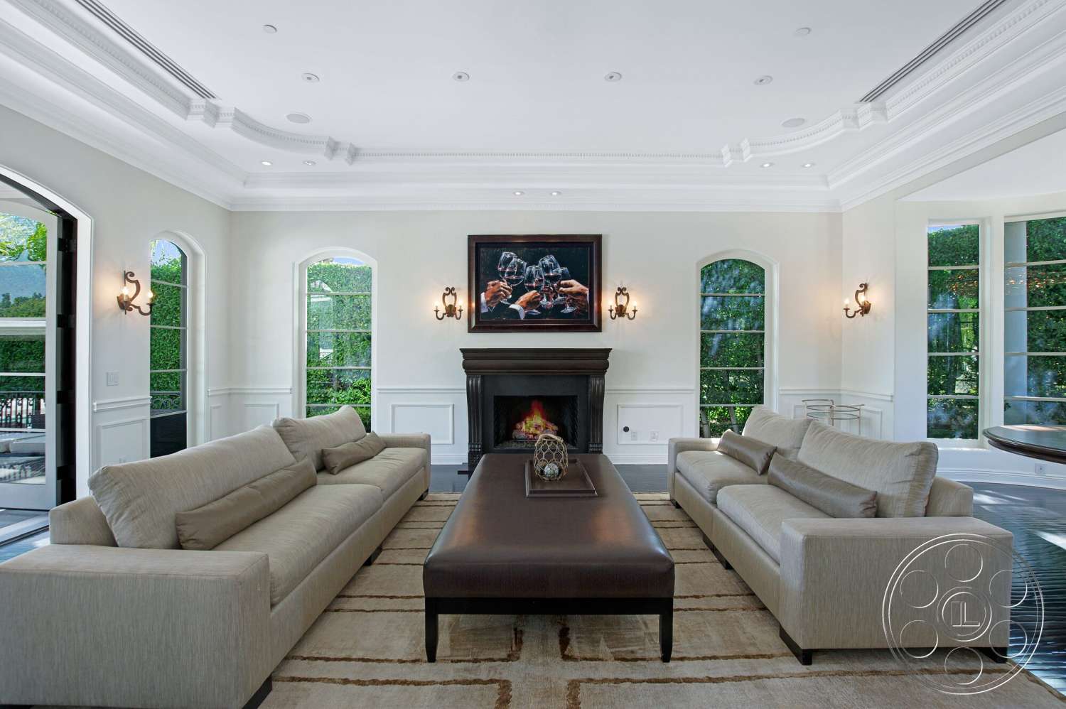 Medit 170 - neutral color palette, natural light, contemporary artwork, floor-to-ceiling windows, arched doorways, spacious living room, dark wood coffee table, white painted walls, stone fireplace wall, vaulted living room ceiling, exposed crown molding details, soft area rug with geometric pattern, sconce lighting fixtures, sofa upholstery fabric