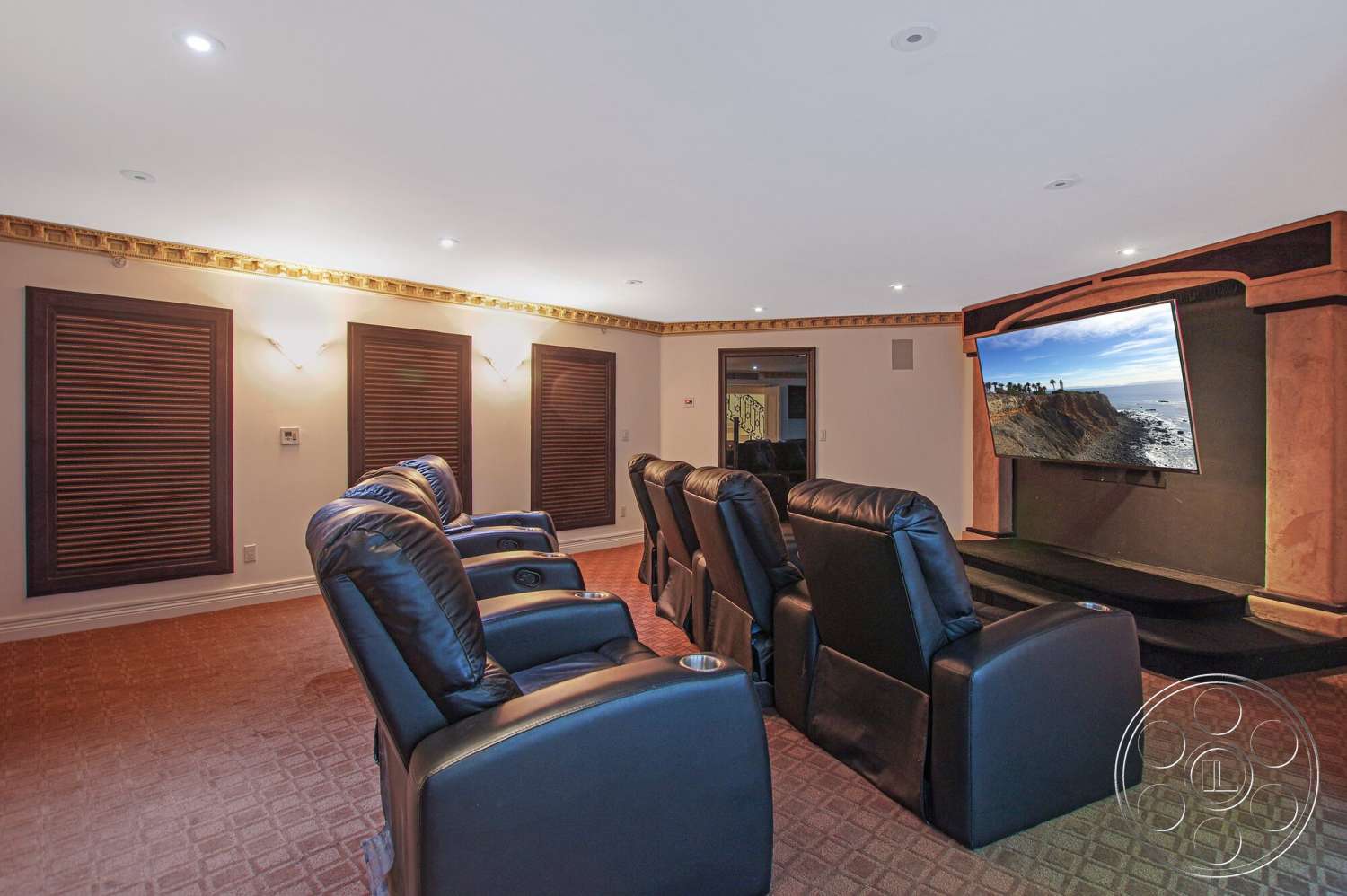 Medit 170 - decorative crown molding, textured plaster walls, dim ambient lighting, coffered ceiling details, acoustic wall panels, built-in wall-mounted television, interior theater room, reclining leather theater seating, carpet flooring in theater room, dark wood window treatments